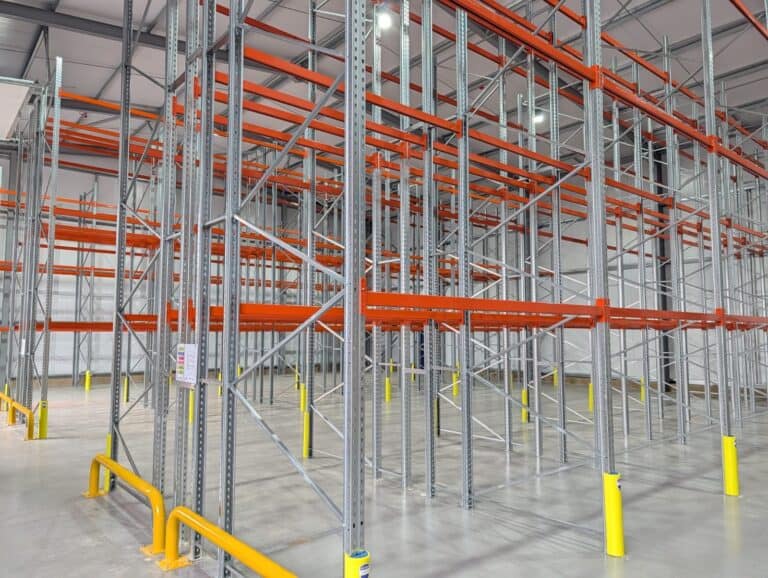 Empty warehouse with grey pallet racking and orange beams on polished concrete floor
